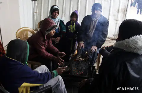 Palestinians, whose houses were destroyed by what they said was Israeli shelling during a 50- day-war last summer, warm themselves around a fire on a stormy day in the east of Khan Younis in the southern Gaza Strip Janua...