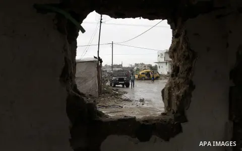Palestinians, whose houses were destroyed by what they said was Israeli shelling during a 50- day-war last summer, stand outside containers used as temporary replacement for their damaged homes, on a stormy day in the ea...
