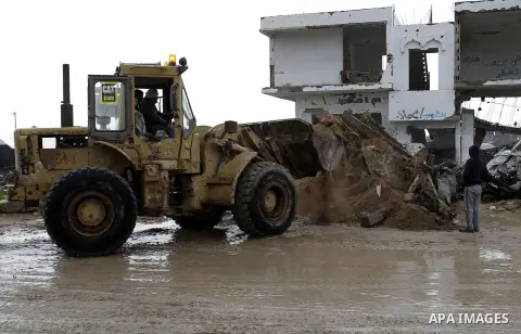 Palestinians, whose houses were destroyed by what they said was Israeli shelling during a 50- day-war last summer, use a bulldozer to remove rubbles on a stormy day in the east of Khan Younis in the southern Gaza Strip J...