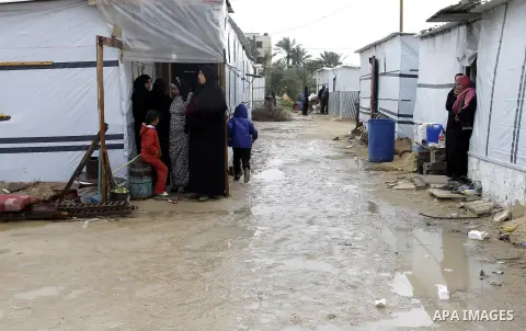 Palestinians, whose houses were destroyed by what they said was Israeli shelling during a 50- day-war last summer, stand outside containers used as temporary replacement for their damaged homes, on a stormy day in the ea...