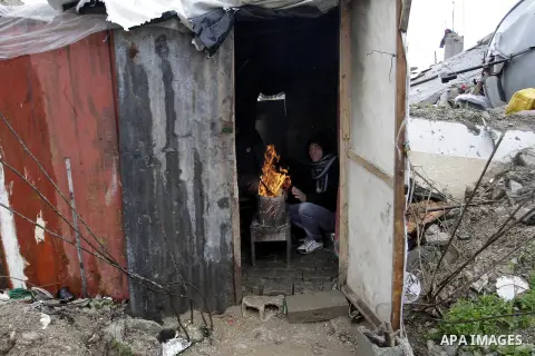 Palestinians, whose houses were destroyed by what they said was Israeli shelling during a 50- day-war last summer, warm themselves around a fire on a stormy day in the east of Khan Younis in the southern Gaza Strip Janua...