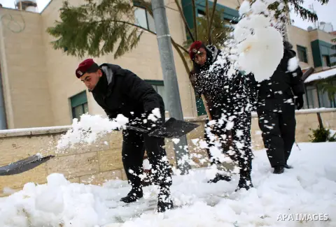 Palestinian security forces remove the snow from a street after a snowfall in the West Bank city of Ramallah, January 8, 2015. A storm buffeted the Middle East with blizzards, rain and strong winds on Wednesday, keeping...
