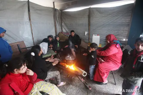 Palestinians warm themselves around a fire at a United Nations (UN) run school sheltering Palestinians, whose houses were destroyed in the 50- day-war Israeli last summer, during a winter storm in Beit Hanoun in the nort...