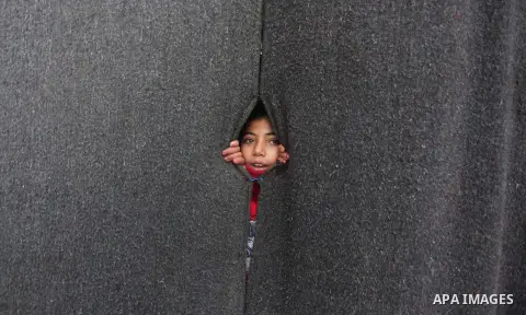 A Palestinian girl looks on behind a curtain at a United Nations (UN) run school sheltering Palestinians, whose houses were destroyed in the 50- day-war Israeli last summer, during a winter storm in Beit Hanoun in the no...