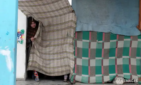 A Palestinian girl looks on behind a curtain at a United Nations (UN) run school sheltering Palestinians, whose houses were destroyed in the 50- day-war Israeli last summer, during a winter storm in Beit Hanoun in the no...