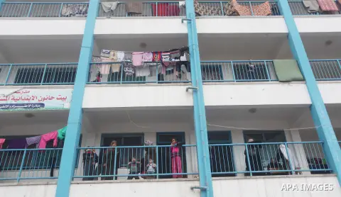 Palestinians stand outside classrooms at a United Nations (UN) run school sheltering Palestinians, whose houses were destroyed in the 50- day-war Israeli last summer, during a winter storm in Beit Hanoun in the northern...