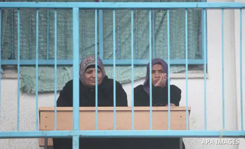 Palestinian women sit outside classrooms at a United Nations (UN) run school sheltering Palestinians, whose houses were destroyed in the 50- day-war Israeli last summer, during a winter storm in Beit Hanoun in the northe...
