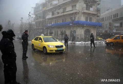 Palestinians walk in a street during a snowfall in the West Bank city of Ramallah, January 9, 2015. A storm buffeted the Middle East with blizzards, rain and strong winds on Wednesday, keeping people at home across the r...