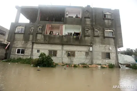 A Palestinian man walks in a flooded street following heavy rain in Rafah in the southern Gaza Strip January 9, 2015. Heavy rains and near-freezing temperatures in the approaching storm threatened to deepen the misery in...