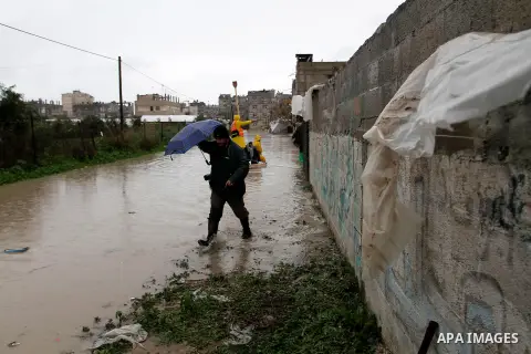 A Palestinian man walks in a flooded street following heavy rain in Rafah in the southern Gaza Strip January 9, 2015. Heavy rains and near-freezing temperatures in the approaching storm threatened to deepen the misery in...