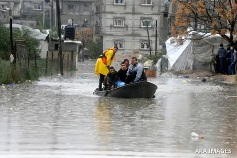 Members of Palestinian Civil Defence ride a boat as they evacuate people following heavy rain that flooded their houses in Rafah in the southern Gaza Strip January 9, 2015. Heavy rains and near-freezing temperatures in t...
