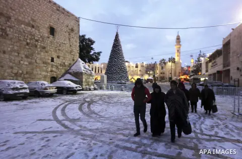 Foreign tourists walk past the Church of the Nativity during a winter storm in the West Bank city of Bethlehem on January 10, 2015. With northern Israel already blanketed in white and flurries reported across wide swathe...