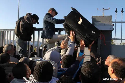 Palestinians, hoping to cross into Egypt, climb a wall as policemen loyal to Hamas stand guard at the Rafah crossing between Egypt and the southern Gaza Strip January 20, 2015. Egyptian authorities opened Rafah crossing,...