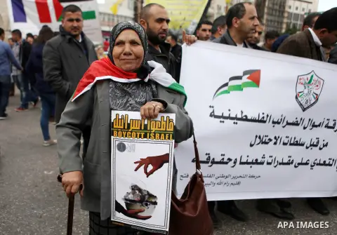 Palestinians hold placards during a rally organised by Fatah movement to support President Mahmoud Abbas' policy and calling to boycott Israeli goods, in the West Bank city of Ramallah, January 26, 2015. Photo by Shadi H...