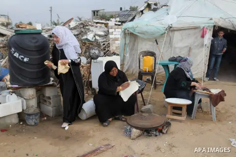 Palestinian women bake bread on firewood outside a tent near the ruins of their houses which witnesses said were destroyed by Israel shelling during a 50-day conflict last summer, east of Khan Younis in the southern Gaza...