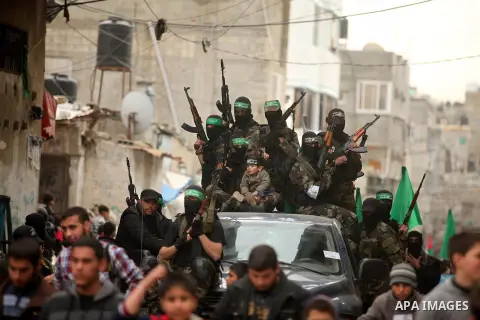 Palestinian members of Ezz Eddin al-Qassam brigades hold weapons as they march during a protest rally in support of the Prophet Mohammed in Gaza City on January 27, 2015. Photo by Ashraf Amra