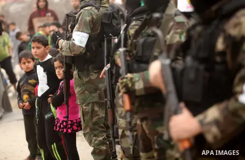 Palestinian members of Ezz Eddin al-Qassam brigades hold weapons as they march during a protest rally in support of the Prophet Mohammed in Gaza City on January 27, 2015. Photo by Ashraf Amra