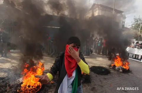 Palestinians burn tires during a protest against the decision by the main U.N. aid agency to suspend payments to tens of thousands of Palestinians for repairs to their homes damaged in last summer's war, outside the head...