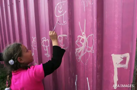 A Palestinian girl paints the container of her family near their house, which was destroyed by Israeli shelling during a 50-day conflict last summer, east if Khan Younis in the southern Gaza Strip, January 28, 2015. Doze...