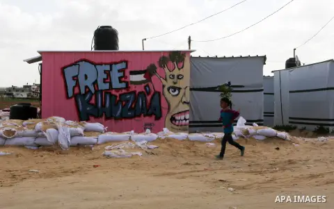 A Palestinian boy plays outside his family's container, which their house was destroyed by Israeli shelling during a 50-day conflict last summer, east if Khan Younis in the southern Gaza Strip, January 28, 2015. Dozens o...