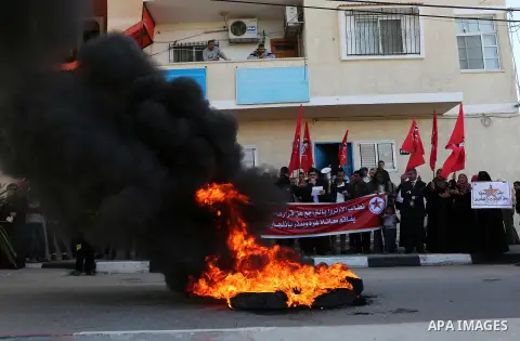 Palestinian protesters burn tires during a protest organised by the Democratic Front for the Liberation of Palestine against United Nations, after the UN announced a lack of funds to rebuild the Palestinian territory, ou...