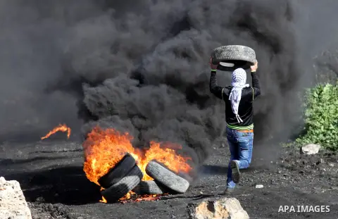A Palestinian protester burns tires during clashes with Israeli security forces during clashes following a demonstration against the expropriation of Palestinian land by Israel in the village of Kfar Qaddum, near Nablus...