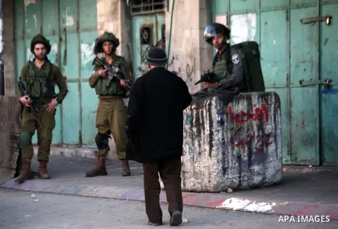 A Palestinian man walks past Israeli soldiers as they stand guard during a demonstration organised by Palestinian protesters against the visit of Israeli President Reuven Rivlin to attend the dedication ceremony of the H...