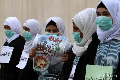 Palestinian students hold signs and a poster reading in Arabic: "no for pollution" as they protest against Israeli factories set up in the Nitzanei Shalom industrial area near the West Bank Palestinian village of Tulkare...