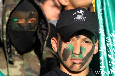 Palestinian youths wear military-style uniforms during a rally to condemn the decision of an Egyptian court to ban the armed wing of Palestinian Islamist movement, near the Rafah border between southern Gaza Strip and Eg...