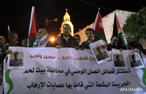Palestinians hold candles and portraits of slain Jordanian pilot, Lt. Muath al-Kasasbeh, killed by the Islamic State group, during a candle light vigil outside the Nativity Church in the West Bank city of Bethlehem, Febr...
