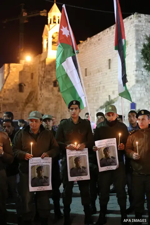 Palestinian security forces hold candles and portraits of slain Jordanian pilot, Lt. Muath al-Kasasbeh, killed by the Islamic State group, during a candle light vigil outside the Nativity Church in the West Bank city of...
