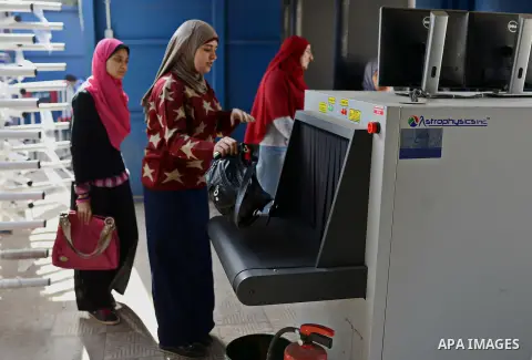 Egyptian students push their bags at an X-ray machine for screening at the entrance of Cairo University during the first day of the second term of the 2014-15 academic year on February 7, 2015. Due to the escalation of s...