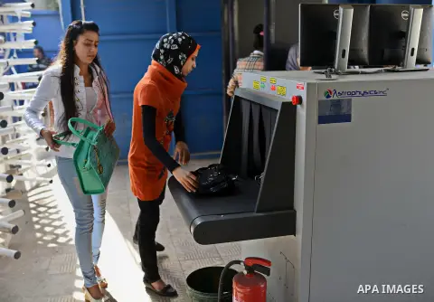 Egyptian students push their bags at an X-ray machine for screening at the entrance of Cairo University during the first day of the second term of the 2014-15 academic year on February 7, 2015. Due to the escalation of s...