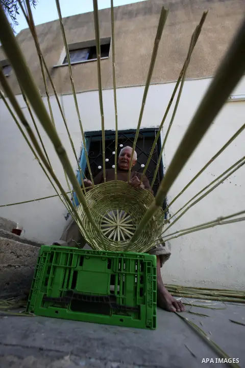 Palestinian Abu Ali Salhat, 80, works on a traditional straw basket, at his house near the West Bank city of Nablus, February 8, 2015. Photo by Nedal Eshtayah