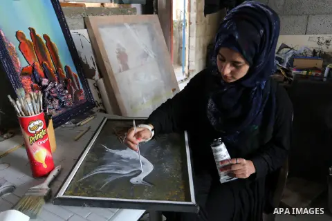 A Palestinian girl paints a picture at an atelier in Rafah in the southern Gaza Strip, February 9, 2015. Three Palestinian artists use the remains of houses which were destroyed during the 51 day Israeli recent war on Ga...
