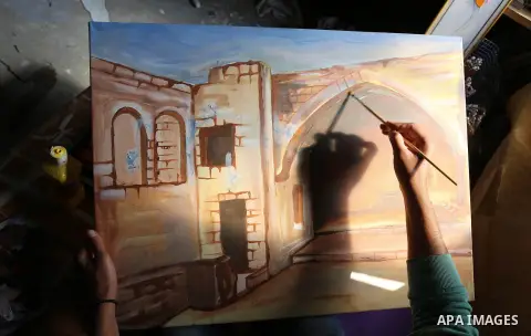 A Palestinian man paints a picture at an atelier in Rafah in the southern Gaza Strip, February 9, 2015. Three Palestinian artists use the remains of houses which were destroyed during the 51 day Israeli recent war on Gaz...