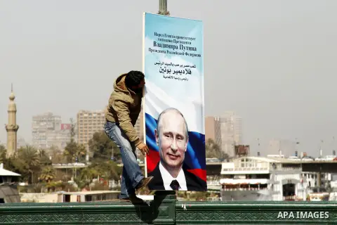 An Egyptian worker adjusts a banner displaying the portrait of Russian President Vladimir Putin on a Cairo's 6th of October bridge on February 9, 2015. Russian President Vladimir Putin visits Egypt on February 10 for a t...