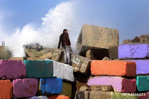 A Palestinian man stands on breaks as a huge wave crash over a sea wall at the Gaza seaport during a stormy day, east Gaza city on February 12, 2015. Photo by Yasser Qudih
