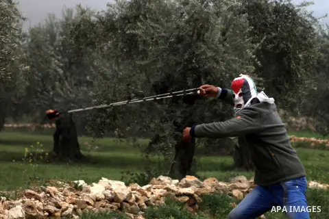 A masked Palestinian protester uses a sling shot to throw stones towards Israeli border policemen during clashes following a demonstration against Jewish settlements in the West Bank village of Bilin, near Ramallah Febru...
