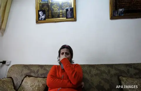 The mother of Arab-Israeli Muhammad Said Ismail Musallam cries as she sits under a photo of her son, who is captured by the Islamic State (IS) group allegedly for spying for Israel's Mossad foreign intelligence agency, o...