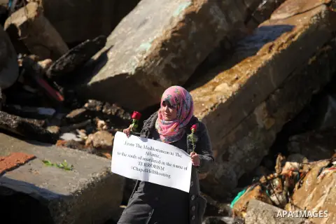 A Palestinian woman carrying flowers gathers at the sea of Gaza City, on February 14, 2015. Three young Muslims were gunned down in Chapel Hill, North Carolina, this week. Newlywed Deah Shaddy Barakat, 23, a University o...