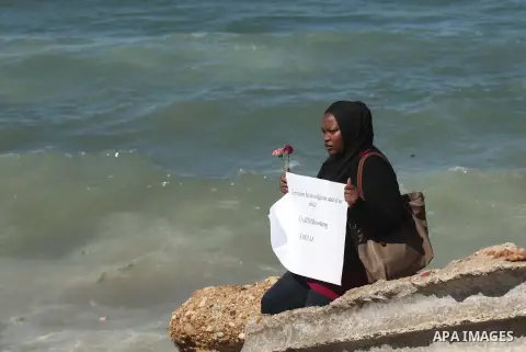 A Palestinian woman carries flowers gathers at the sea of Gaza City, on February 14, 2015. Three young Muslims were gunned down in Chapel Hill, North Carolina, this week. Newlywed Deah Shaddy Barakat, 23, a University of...