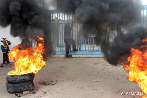 Smoke rises from burning tyres as Palestinians shout during a protest calling for reconstruction of their houses that witnesses said were destroyed by Israeli shelling during a 50-day war last summer, outside a United Na...