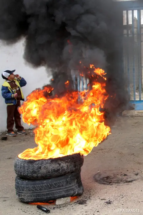Smoke rises from burning tyres as Palestinians shout during a protest calling for reconstruction of their houses that witnesses said were destroyed by Israeli shelling during a 50-day war last summer, outside a United Na...