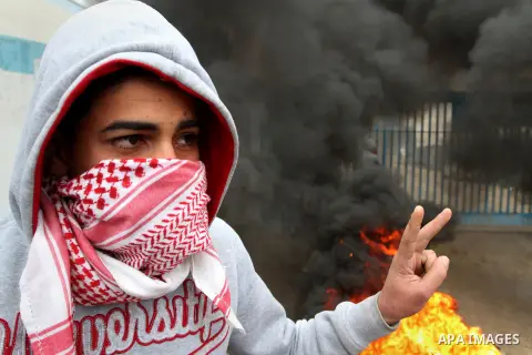 A Palestinian man standing near burning tyres takes part in a protest calling for reconstruction of houses that witnesses said were destroyed by Israeli shelling during a 50-day war last summer, outside a United Nations...