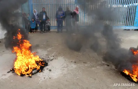 Smoke rises from burning tyres as Palestinians shout during a protest calling for reconstruction of their houses that witnesses said were destroyed by Israeli shelling during a 50-day war last summer, outside a United Na...