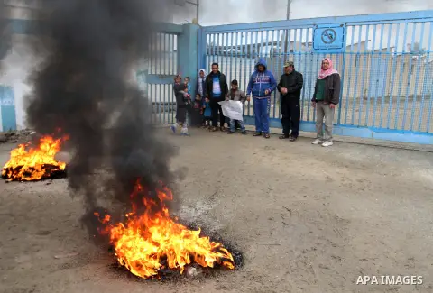 Smoke rises from burning tyres as Palestinians shout during a protest calling for reconstruction of their houses that witnesses said were destroyed by Israeli shelling during a 50-day war last summer, outside a United Na...