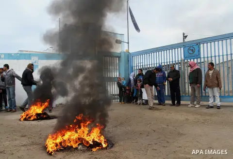 Smoke rises from burning tyres as Palestinians shout during a protest calling for reconstruction of their houses that witnesses said were destroyed by Israeli shelling during a 50-day war last summer, outside a United Na...