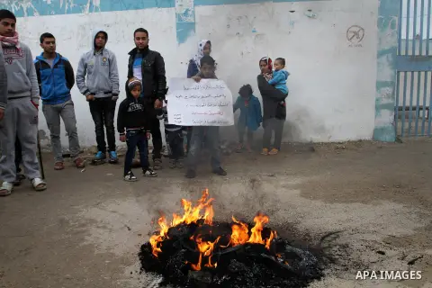 Smoke rises from burning tyres as Palestinians shout during a protest calling for reconstruction of their houses that witnesses said were destroyed by Israeli shelling during a 50-day war last summer, outside a United Na...