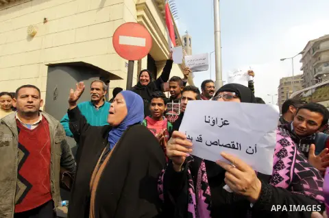An Egyptian woman holds a placard with Arabic inscription reading 'We are consoled as retribution began' to denounce the killing of Egyptian Christians in Libya, outside the Coptic Cathedral of Saint Marcos, in Cairo, Eg...